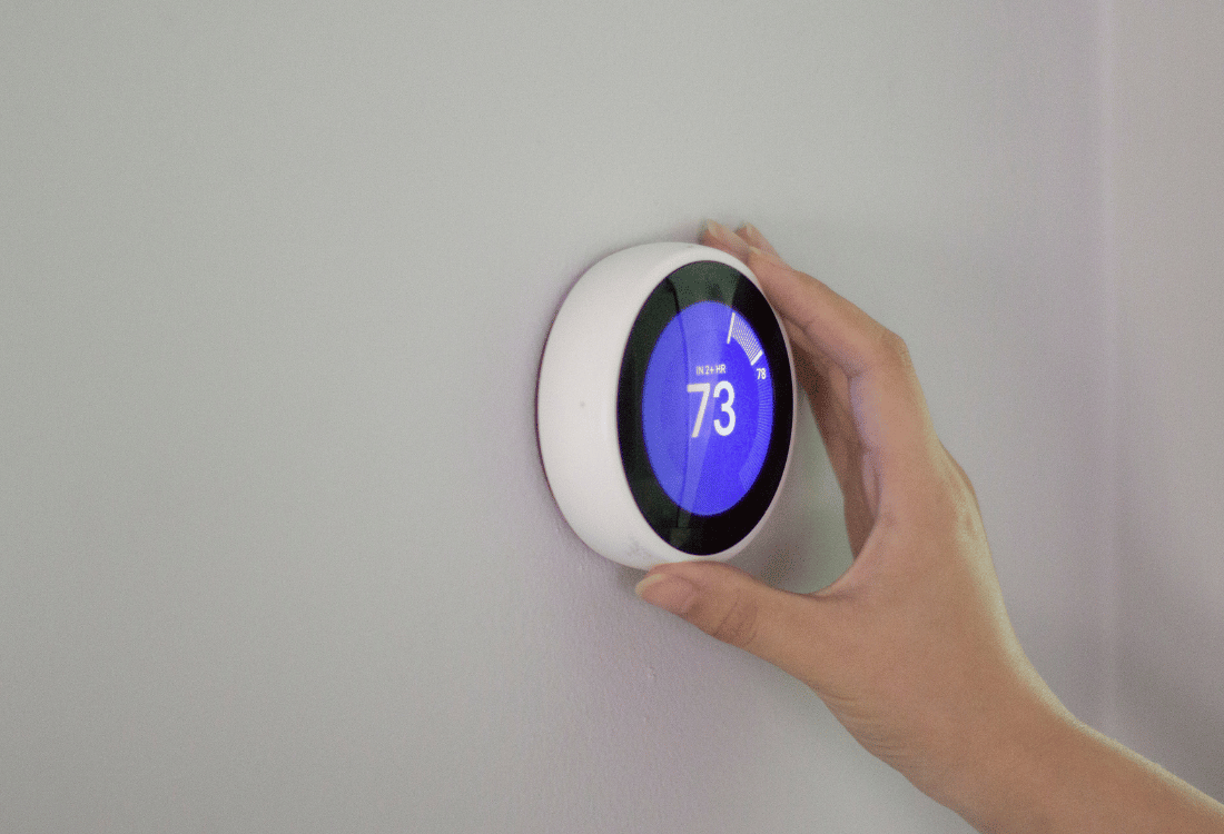 A picture of a woman's hand showcasing the benefits of a smart thermostat. 